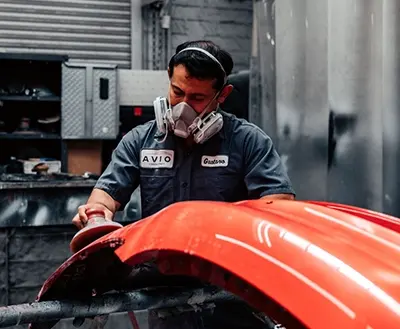 Technician sanding a bumper in preparation for paint at Avio Coach Craft