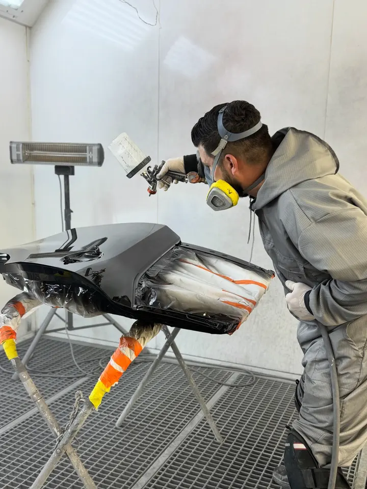 Painter refinishing a bumper in the Classic Collision Downey spray booth
