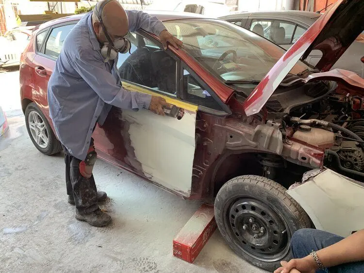 Technician prepping a car door for paint inside the shop
