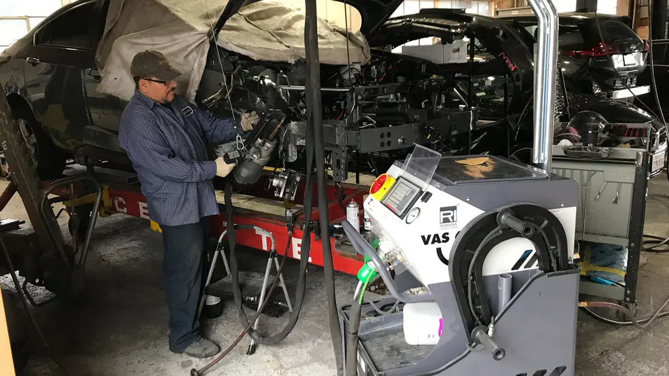 Technician working on a vehicle on a frame bench in the Glendale Auto Body shop