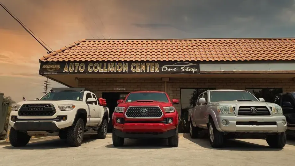 Pickups parked under the One Stop Auto Collision Center sign