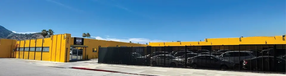 Yellow Straight Auto Body building at 425 W Cypress St with its gated lot